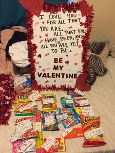 a valentine's day sign surrounded by candy, candies and other items on a bed