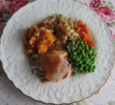 a white plate topped with meat and veggies on top of a floral table cloth