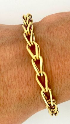 This exquisite bracelet is a true designer piece from Italian luxury brand UNOAERRE. Crafted from high-quality 14k yellow gold, this intertwined etched bracelet is both stylish and durable. The wrap and chain style adds a touch of elegance to any outfit, while the 7.5 inch length ensures a comfortable fit. With no stone and featuring a unique design, this bracelet is perfect for those who want to stand out from the crowd. The piece weighs 5.8g and is stamped with the brand's signature mark. Add Luxury Rectangular Yellow Gold Bracelet, Luxury Yellow Gold Jewelry With Rectangular Links, Luxury Etched Gold Bracelet, Luxury Gold Etched Bracelet, Luxury Rectangular Gold-tone Jewelry, Luxury Gold-tone Rectangular Jewelry, Engraved Oval Yellow Gold Bracelet, Formal Engraved Yellow Gold Chain Bracelet, Formal Yellow Gold Chain Bracelet Engraved