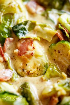 a close up view of broccoli and other vegetables in a sauce with bacon