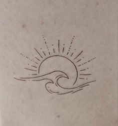 a small sun and wave tattoo on the back of a woman's shoulder