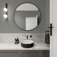 a bathroom sink with a round mirror above it