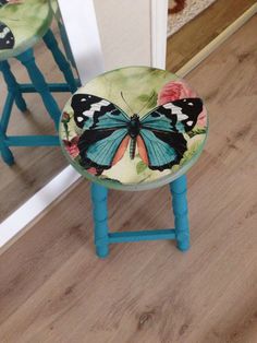 two blue stools with butterflies painted on them in front of a mirror and door