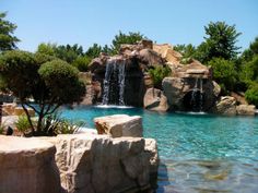 an outdoor pool with waterfall and rocks