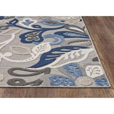 an area rug with blue and white flowers on it, in the middle of a wooden floor