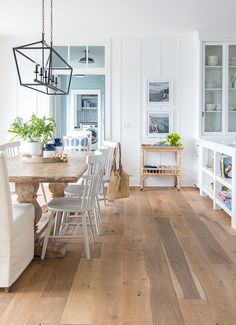 a dining room table with white chairs and wooden floors