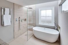 a white bath tub sitting next to a window in a bathroom