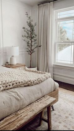 a bedroom with a large bed and a tree in the corner on one side of the bed