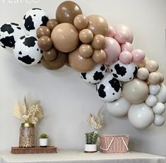 a table topped with lots of balloons and cow heads on top of each balloon wall