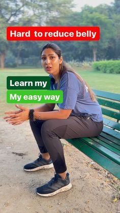 a woman sitting on top of a green bench next to a park filled with trees