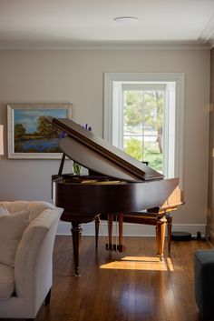 a living room with a grand piano in the corner and a painting on the wall