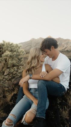 a man and woman sitting on top of a rock