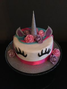 a cake decorated with flowers and a unicorn's horn is on a black table