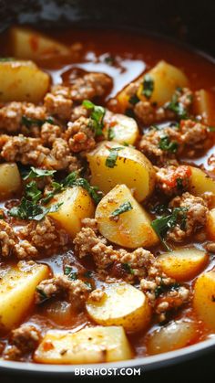 a bowl filled with meat and potatoes covered in sauce