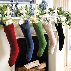 christmas stockings hanging from a mantel with flowers and greenery on them in front of a fireplace