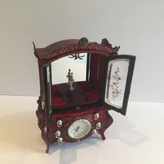 an ornate red clock with mirror and figurine