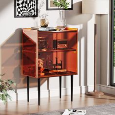 an orange cabinet in the corner of a room with pictures on the wall behind it