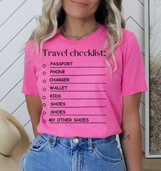 "Travel checklist tshirt, traveling tee, Travel junkie tshirt, funny checklist tee, travel essentials tee, Adventure Shirt, Wanderlust Shirt, Vacation Shirt, Unisex shirt, Travel Gift,  This funny checklist tee is for you if you are travelling or a great gift for a friend.  This unisex t-shirt has a ribbed knit collar to provide a stylish touch and help the tee maintain its shape, while the taped shoulders ensure a better fit over time. And with dual side seams to hold the garment's shape for even longer, this tee is perfect for anyone who wants to look and feel great all day long. Size up for an oversized look! So pack your bags, grab your favorite tee, and let the adventure begin!\" This t-shirt is printed using the latest direct-to-garment technology, ensuring that the design is vibrant Summer Adventure T-shirt With Text Print, Graphic Print Short Sleeve T-shirt For Travel, Summer Travel Cotton T-shirt, Cotton T-shirt For Travel In Summer, Cotton T-shirt For Summer Travel, Cotton Short Sleeve T-shirt For Travel, Graphic Tee For Travel In Summer, Graphic Tee For Summer Travel, Summer Graphic Tee For Travel