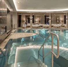 an indoor swimming pool with steps leading up to it and lounges in the background