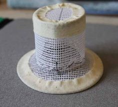 a small white hat sitting on top of a gray table next to a green object