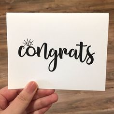 someone holding up a card with the word congrats written on it in black ink