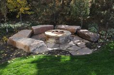 an outdoor fire pit surrounded by rocks and grass