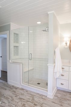 a bathroom with white cabinets and tile flooring in the shower area, along with a walk - in shower