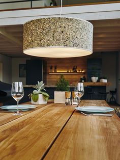 a wooden table with plates and wine glasses on it in front of an open floor plan