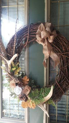 a wreath with antlers and flowers on the front door