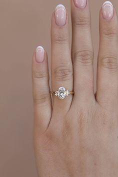 a woman's hand with a diamond ring on top of her left hand,