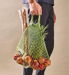 a person holding a bag full of fruit