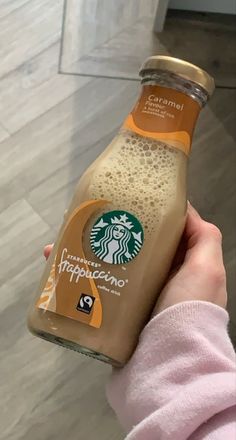 a person holding up a bottle of starbucks's frappuccino coffee drink