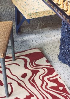 a table with chess pieces on it in front of a rug and chair next to the table