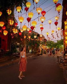 a woman is walking down the street in front of many lanterns