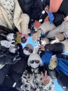 a group of people standing in the snow with their hands up and wearing winter clothing