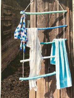 two towels hanging on a clothes line next to a wooden fence with blue and white cloths