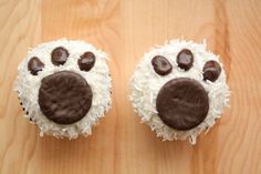 two cupcakes with white frosting and chocolate dog paw prints on the top