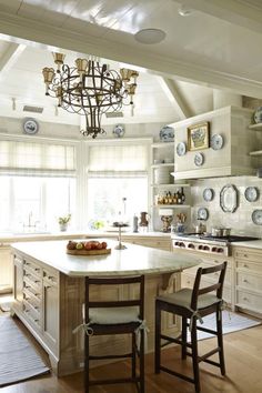 a large kitchen with an island in the center and two chairs at the counter top