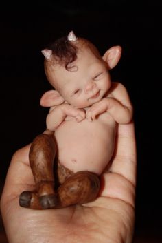 a hand holding a small baby doll in it's palm