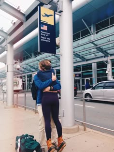 two people hugging each other in front of an airport