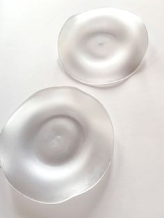 two white plates sitting on top of a table next to each other, one with an empty plate in the middle