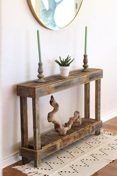 a wooden table with two candles on top and a mirror above it in a room