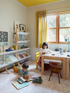 two children sitting at a table with books in front of them and an open window