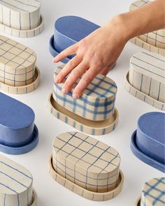 a hand reaching for an object made out of wooden and blue boxes with plaid designs on them