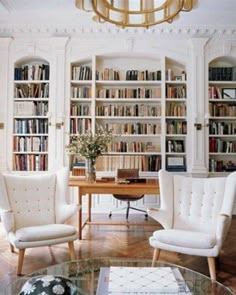 a living room filled with lots of white furniture and bookshelves full of books