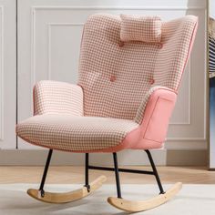 a pink rocking chair in front of a white wall