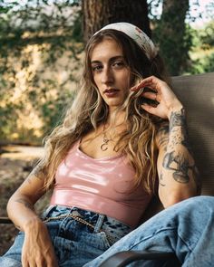 a woman sitting in a chair with tattoos on her arm and headband around her neck