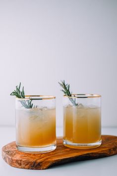 two glasses filled with drinks sitting on top of a wooden tray