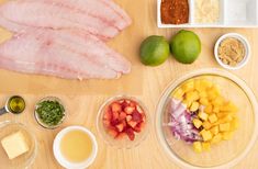 the ingredients to make this dish are laid out on a wooden surface, including meat, fruit, and seasonings