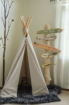 a teepee tent sitting on top of a rug next to a wooden sign